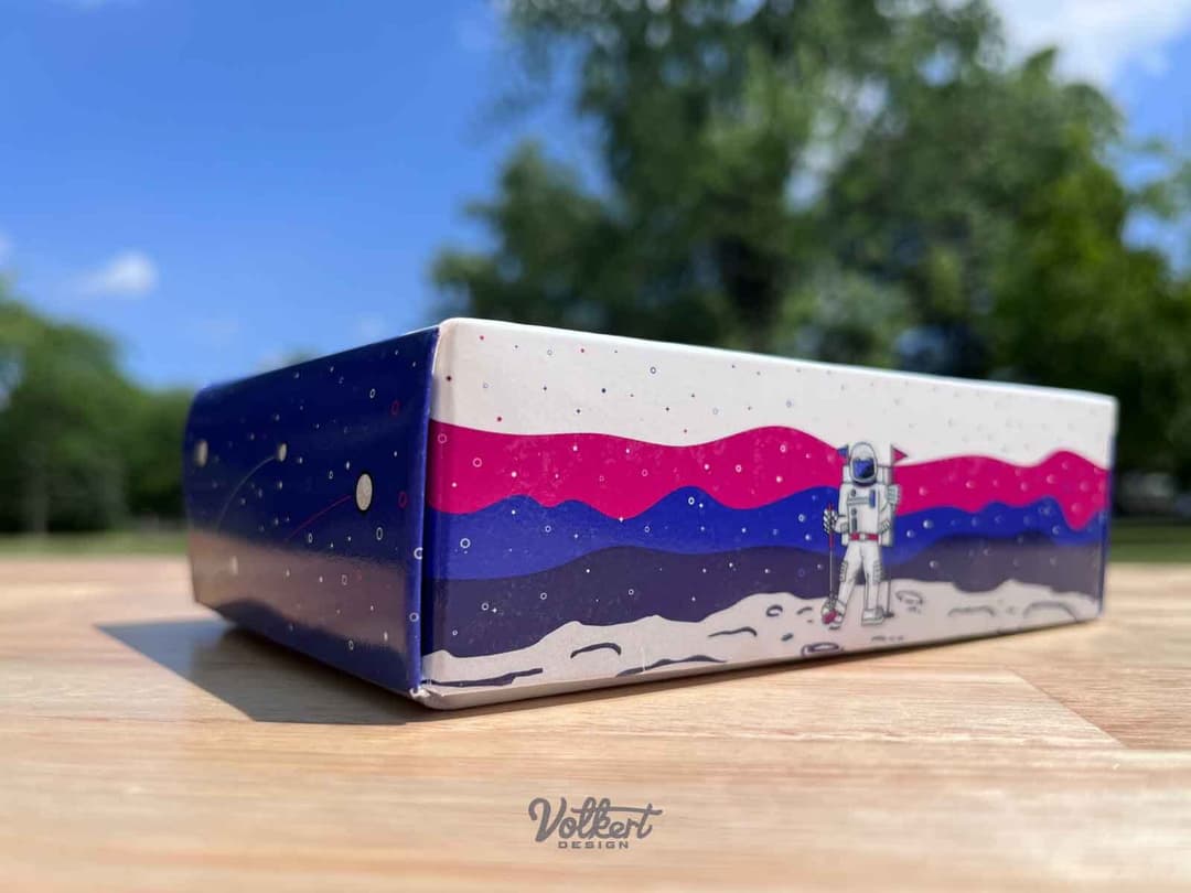 A golfing astronaut holds a golf flag on the long side of the promotional golf box.