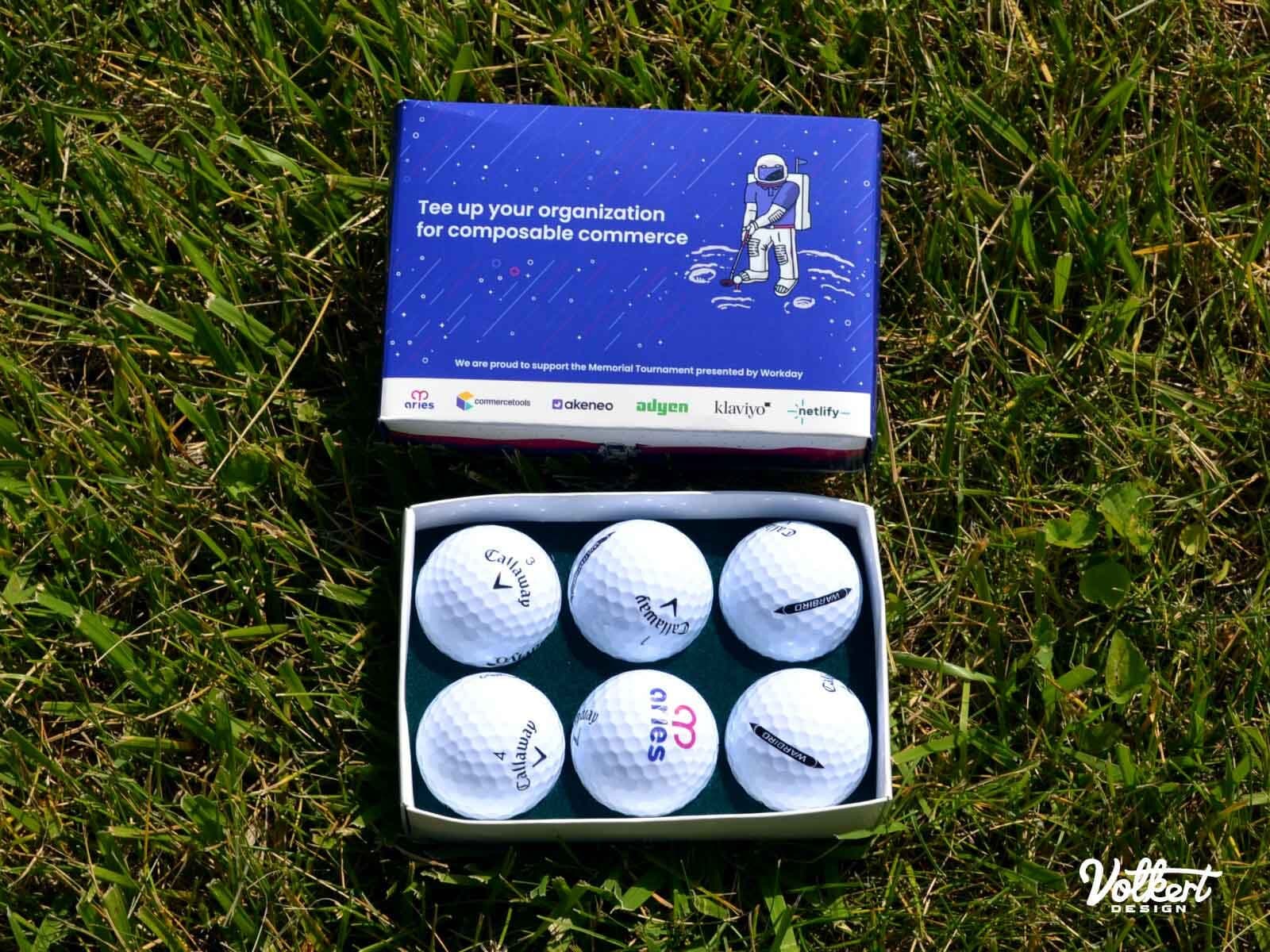 A photo of a baker's dozen of promotional golf balls in the green grass.