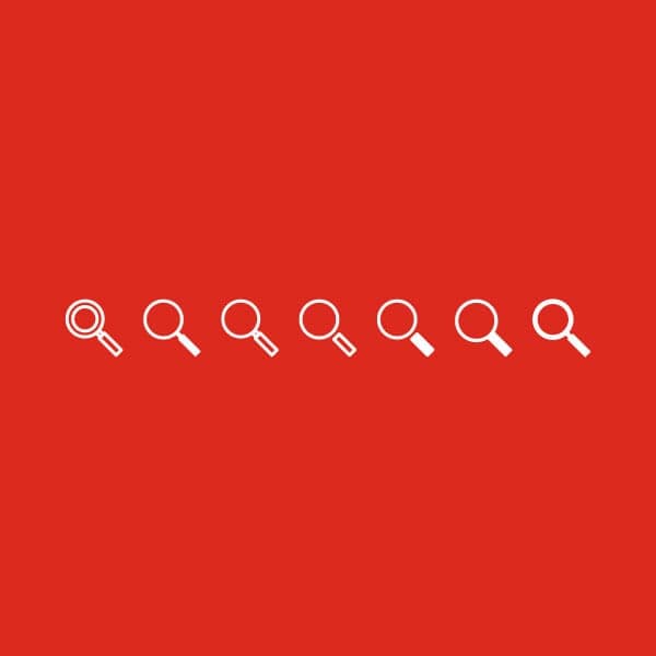 Various looks of white magnifying glass icons on Grainger red to determine the best icon design.